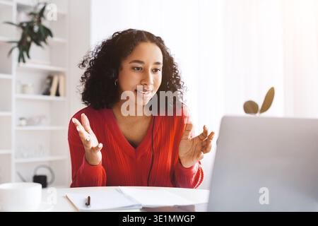 Young Woman Talking During a Virtual Meeting in Her Home Office in the Morning Light Stock Photo