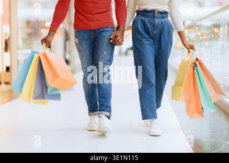 Couple Holds Hands While Shopping in a Mall During the Day With Colorful Bags Stock Photo
