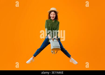 Woman Jumps With Excitement Holding Bag Against an Orange Background Stock Photo