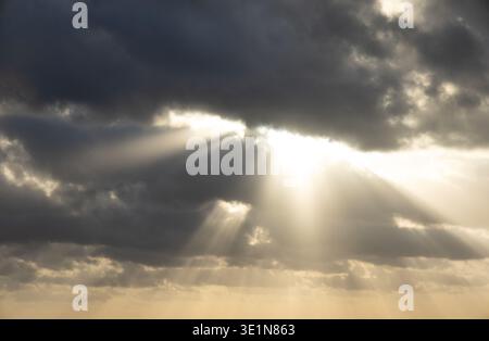 Sun rays streaming through dramatic clouds over the Caribbean Sea near Cozumel, Quintana Roo, Mexico, creating beams of light across the sky and water Stock Photo