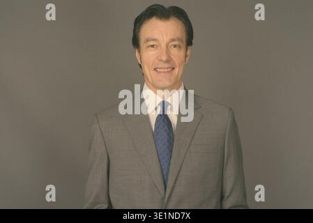 Studio shot of mature handsome businessman against gray background Stock Photo