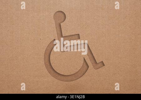 Handicap disability wheelchair symbol embossed on brown cardboard texture background Stock Photo
