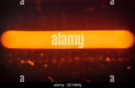 Abstract image of a blurred orange light strip against a dark background, showcasing a glowing horizontal line with subtle texture and depth Stock Photo