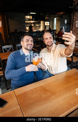 Two men friends taking selfie in pub with beers Stock Photo