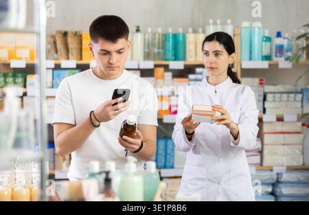 Man buyer scans syrup qr code with woman pharmacist Stock Photo