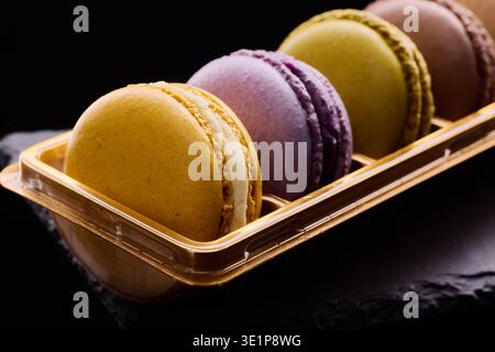 Colorful macarons tasty biscuits on black background. Traditional french dessert, gourmet confectionery pastry Stock Photo