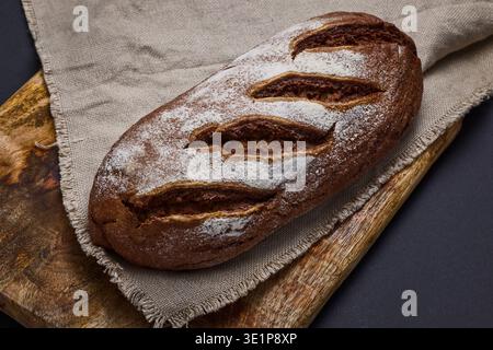 Rustic Sourdough Bread Loaf on Wooden Board with Flour Dusting and Linen Cloth Stock Photo