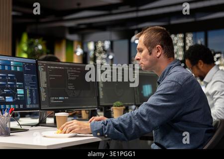 Software developer writing code, developing machine learning APIs. IT professional in tech startup working to troubleshoot software errors using artificial intelligence, resolving system crashes Stock Photo