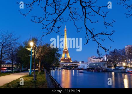 Paris, France-15 March , 2026 : The Eiffel Tower lit up at night with tree branches in the foreground. Paris, France. Stock Photo