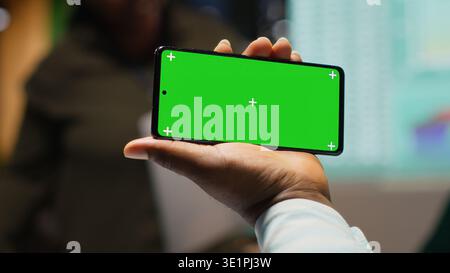 Team members meeting after hours next to isolated smartphone screen, attending an advisory board briefing session to build a strategy and setting goals for project agenda. Camera A. Stock Photo