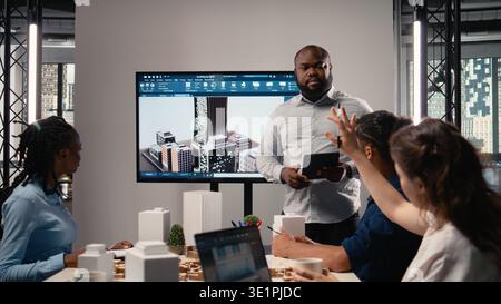 Property developer leads the planning session with 3D models for details and zoning regulations, focusing on site development and infrastructure growth for housing and urban development. Stock Photo