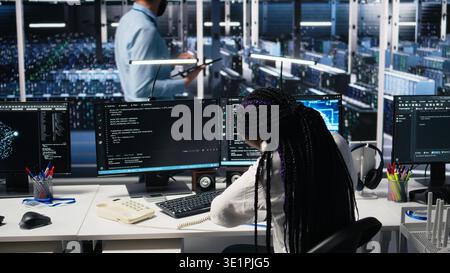 Data center admin receiving phone call, using AI assistant to provide user technical support. Server hub IT professional answering telephone calls assisted by large language model chatbot, camera A Stock Photo