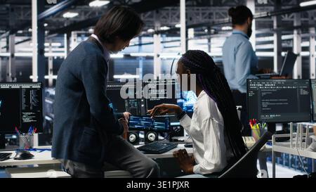 Senior engineer and trainee in data center working on neural network software development. Lead programmer and intern in server room implementing machine learning technology using PC, camera A Stock Photo