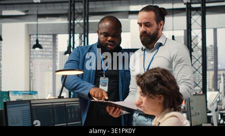 Diverse corporate staff working together on report writing in the office, collaborating on building a new development strategy. Reviewing insights to enhance efficiency and progress. Stock Photo