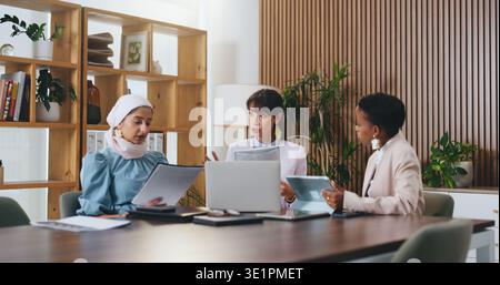 Woman, laptop and documents with team in office meeting for strategy, tablet and insight at insurance company. Person, broker and diversity with tech Stock Photo