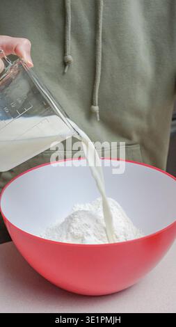 Individual wearing a green hoodie is pouring oil from a glass container ...