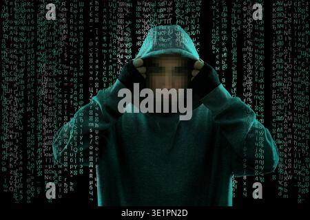 Hacker wearing hood and programming code running through him. Cyber criminal Stock Photo