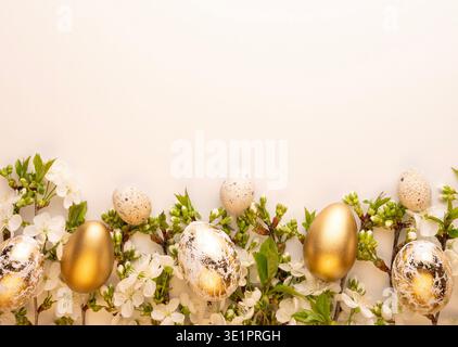 Gold and speckled eggs are arranged on a simple surface with white flowers and green leaves. This setup is for a spring celebration or Easter decorati Stock Photo