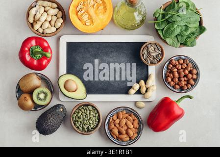 Healthy foods containing vitamin E (Tocopherolum). Natural sources of vitamin E on a light background with chalkboard, top view. Stock Photo