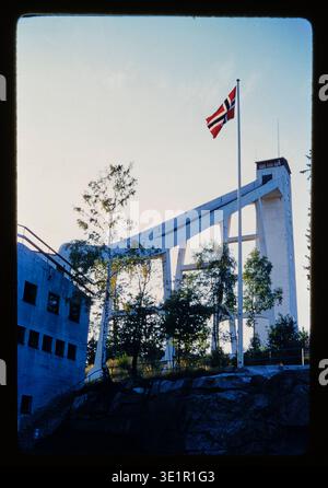 View of the Olympic ski jump, looking up from the bottom, with flying flag. In Oslo, Norway. This slide, Kodachrome image was taken by an American tourist on a trip to Europe in 1959. The color in the photograph is vibrant, almost hand-tinted, painted. Stock Photo