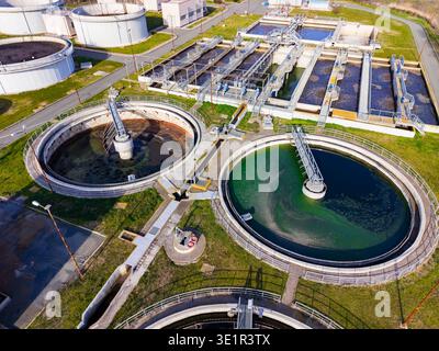 A water treatment facility shows large circular tanks and other structures. It processes wastewater and treats water for community use. The scene is b Stock Photo