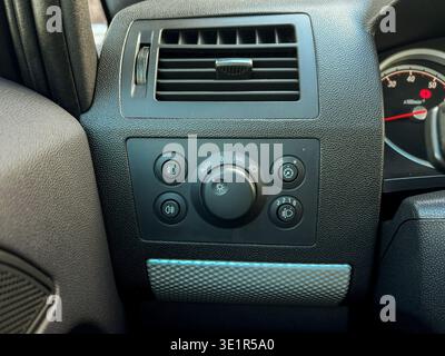 The front control panel shows various knobs and buttons used to adjust temperature and air settings in a vehicle. The sunlight shines on the dashboard Stock Photo