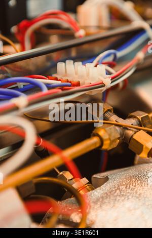 Close view of wires and plumbing on an industrial machine showing connections. Various colored wires are seen alongside metallic components during rou Stock Photo