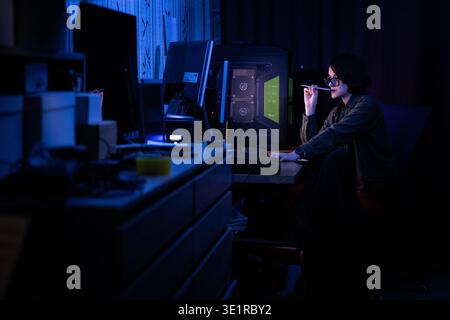 Thoughtful Woman at Desk with Pencil in Dark Room Stock Photo