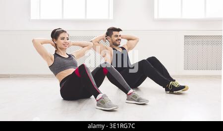 Young couple doing sport exercises on the floor in white studio Stock Photo