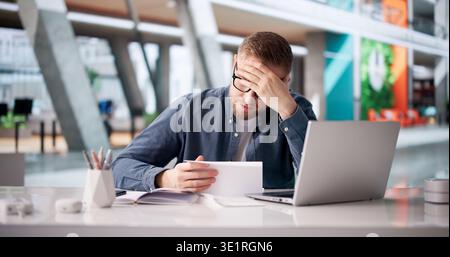 Stressed Young Man Reacting To Troubling Document At Workstation Stock Photo