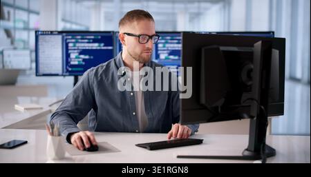 Focused Software Engineer Programming At Desk In Modern Office Stock Photo