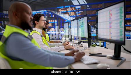 Young Warehouse Worker Uses Computer Software To Track Shipments Efficiently. An Analyst Reviews Inventory Data Stock Photo