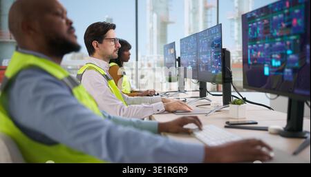Young Engineer Operates Industrial Automation System On Computer, Ensuring Safety. Technician Monitors Data Processing Stock Photo