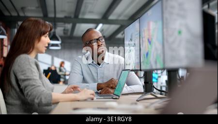 Young Professionals Analyze Urban Traffic Flow Using Digital Mapping And Design Software. Two Engineers Collaborate Stock Photo