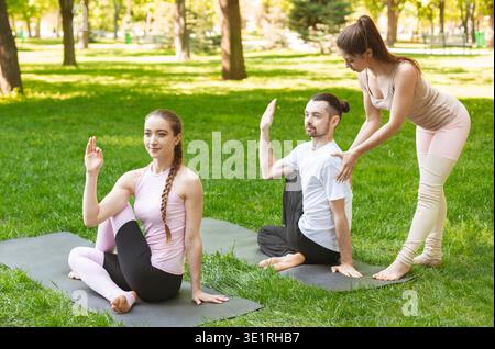 Female yoga teacher helping to improve exercise to beginner Stock Photo