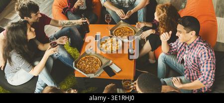 Group of Friends Enjoying Food and Drinks Around a Table in a Cozy Setting During an Evening Stock Photo