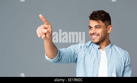 Cheerful Hispanic Man Touching Invisible Screen Interface Stock Photo