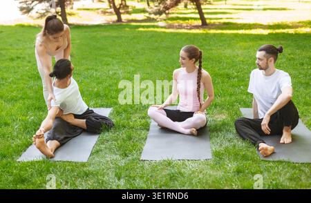 Yoga teacher helping young man to stretch muscles during exercise Stock Photo