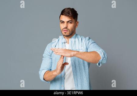 Man Making Time Out Gesture On Gray Background Stock Photo