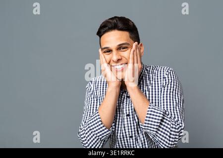 Happy Surprised Man Holding Face In Palms Over Gray Background Stock Photo
