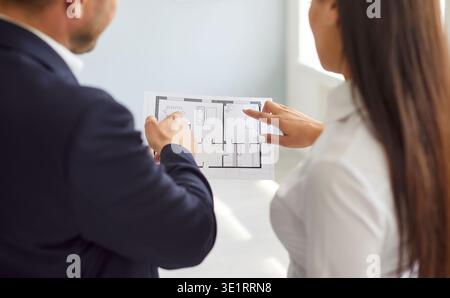 Man designer showing to homeowner woman blueprint with design project or repair of new apartment. Stock Photo
