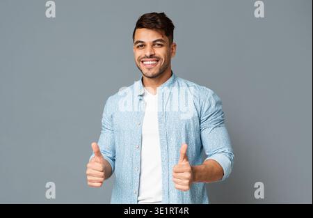 Smiling Guy Showing Thumbs Up With Both Hands Stock Photo