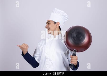 Chef in white uniform holding a pan and gesturing Stock Photo
