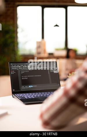 Closeup of african american freelancer writing programming scripts on digital device at home. IT specialist seated at desk with laptop, developing and troubleshooting code for internet security. Stock Photo
