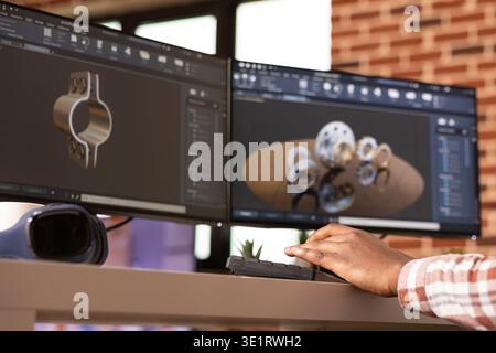Black engineer focused on digital prototyping and 3D simulation of construction components. Remote african american cad designer analyzing project designs at desk in brick wall apartment. Stock Photo