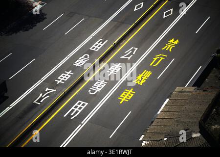 Overhead diagonal view of a Taiwan urban road surface featuring bold white and yellow painted lane markings, a dedicated bus-only lane. Stock Photo