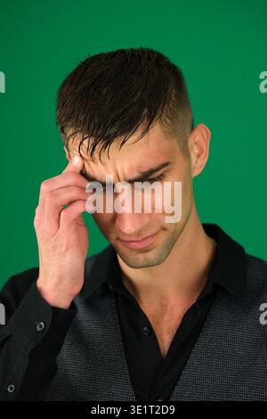 Young designer deep in thought with a hand on his chin while working on a laptop alone at a desk in a modern office. High quality photo Stock Photo