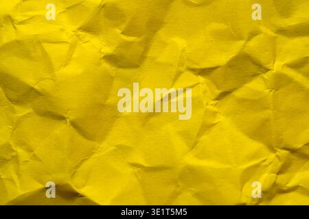 A vibrant yellow surface showcases intricate folds and shadows in bright light. Stock Photo