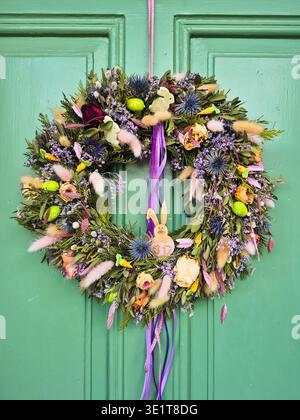 Easter floral wreath hanging on a green door Stock Photo
