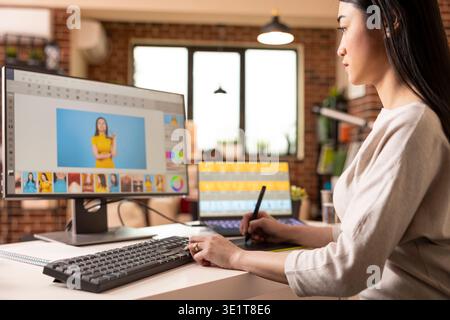 Talented graphic editor adjusts design features and retouches images using drawing tablet. Asian female photographer updating portfolio, working precisely on visual content from home studio. Stock Photo
